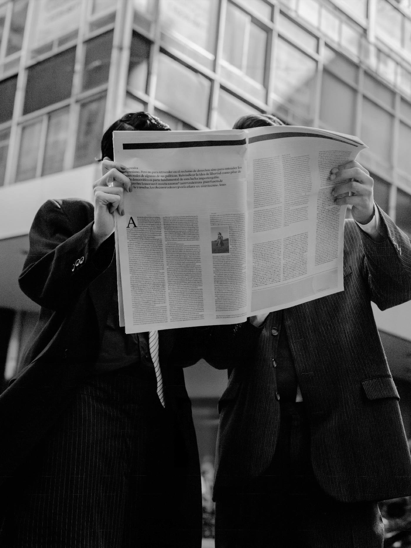 Dos personas de pie con un periódico abierto